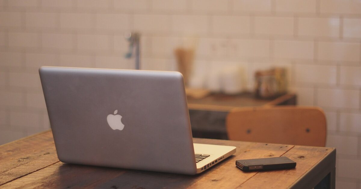 IPhone and laptop arranged on a clean office desk