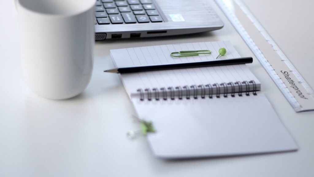 Laptop, notebook and pencil arranged on a clean work desk