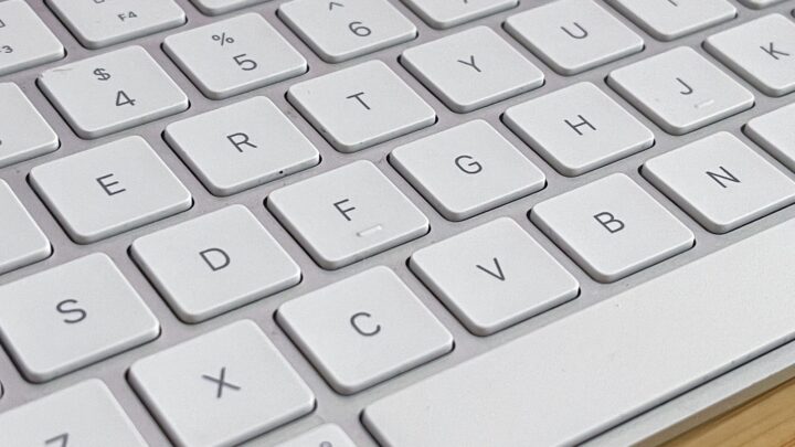 White Apple keyboard on a bamboo desktop.