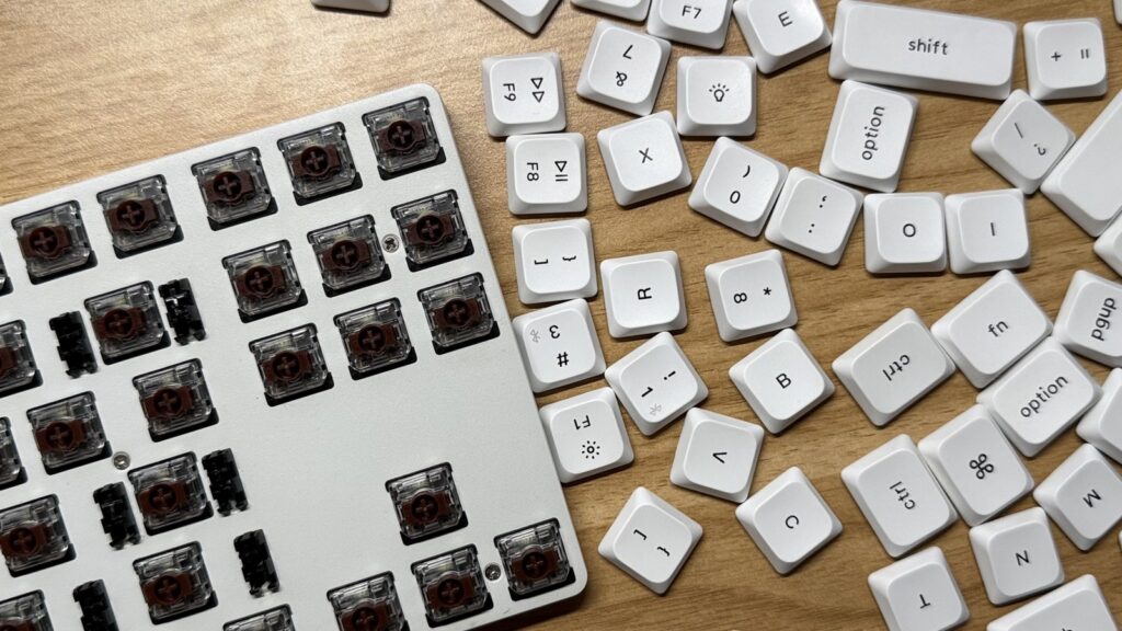 Low-profile mechanical keyboard with brown switches and keycaps being removed on a table.