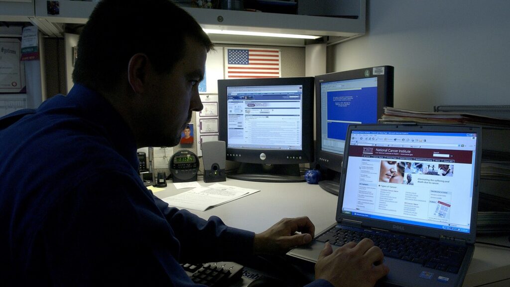 Title man uses laptop description a caucasian male uses his laptop computer at his desk in a darkened room.