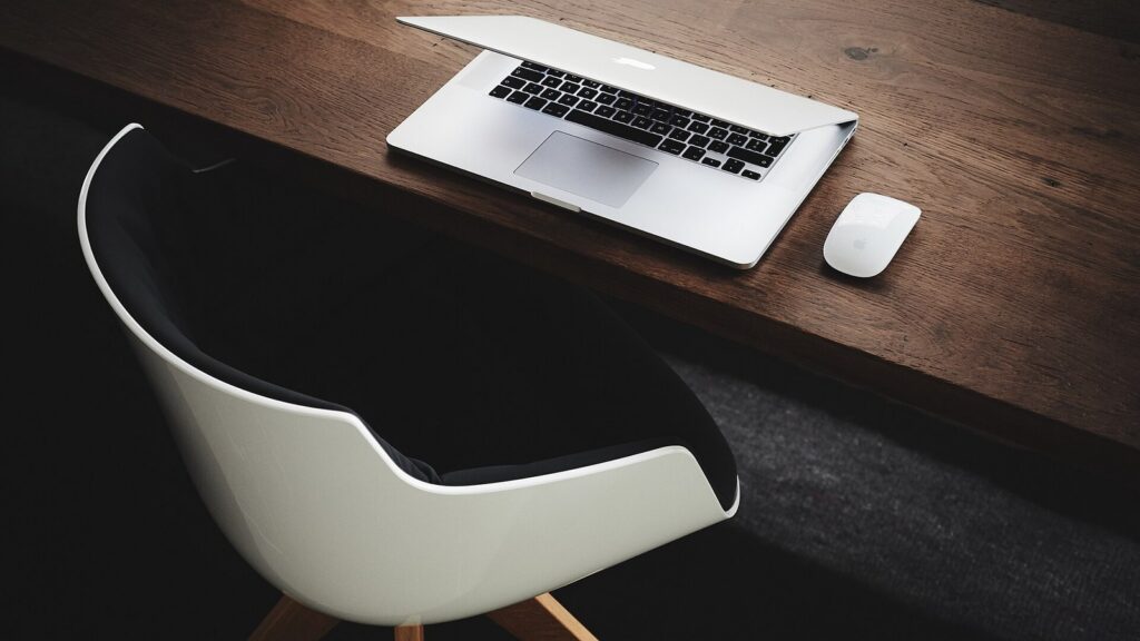 Minimal laptop and mouse workspace on a wooden desk