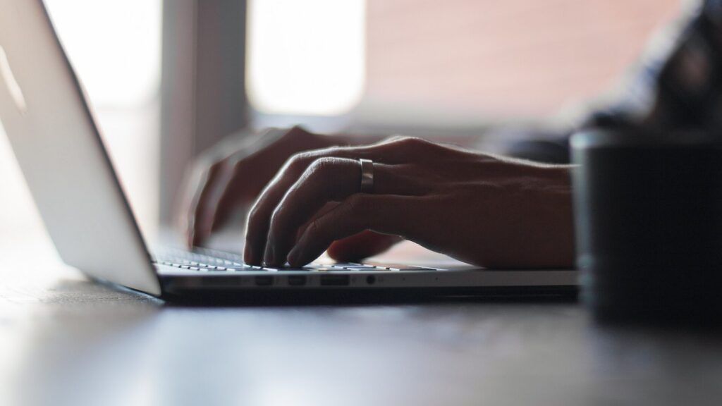 Hands typing on a laptop keyboard.