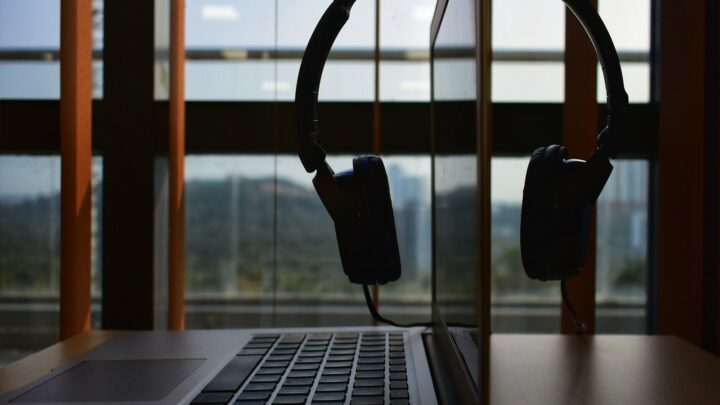 A work desk in a city office with a macbook air and a headset hanging over the screen.