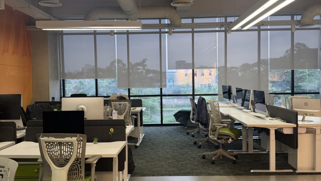 Spacious office with white desks and gray office chairs arranged in rows.