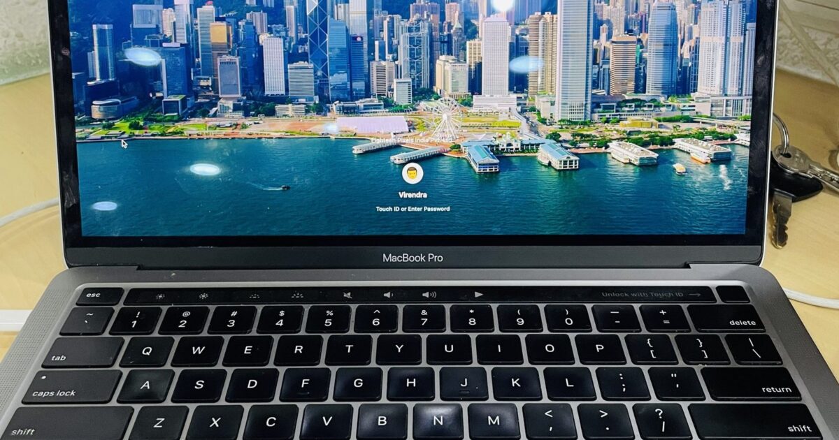 MacBook Pro laptop displaying a cityscape wallpaper with the time 3:33 on the lock screen