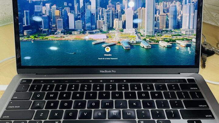MacBook Pro laptop displaying a cityscape wallpaper with the time 3:33 on the lock screen