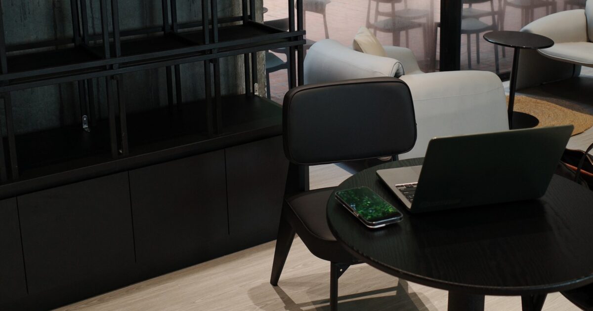 A sleek black table featuring a modern laptop positioned on its surface, showcasing a minimalist workspace.