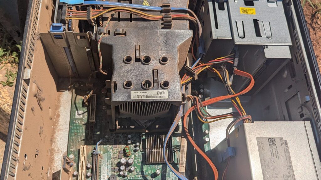 An open desktop computer case showing internal components, including a motherboard, power supply, cables, and a cooling fan.